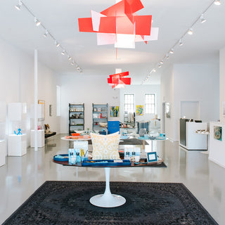 interior of the atelier modern gallery featuring an open, clean, and bright white space colored with curated arts and objects along with red acrylic lights above